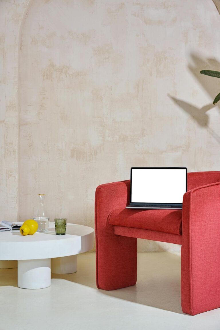 A contemporary workspace featuring a red chair with a laptop offering ample copy space.