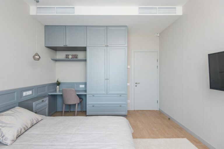 A sleek and modern bedroom with an integrated workspace featuring pastel blue cabinetry.