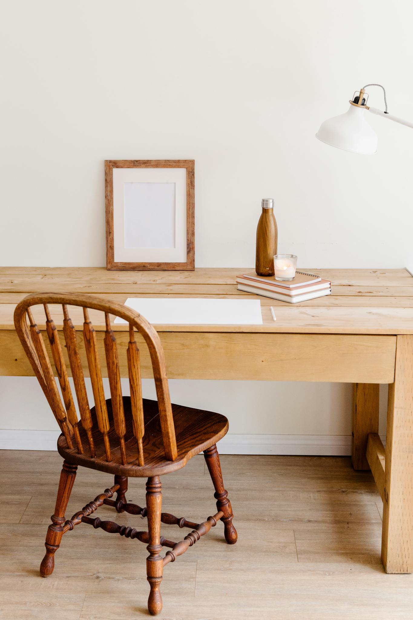 Minimalist workspace setup with a wooden desk, chair, and simple decor elements.